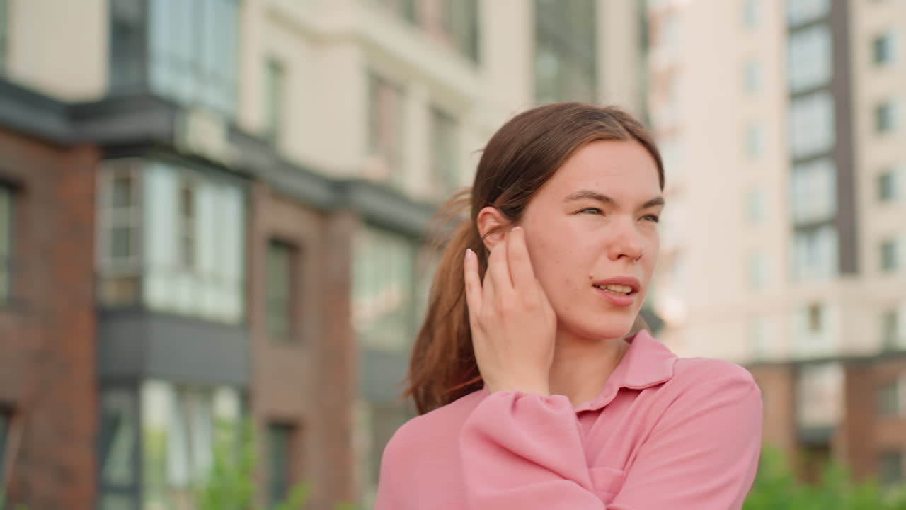City Woman Styling, Woman On Street Tidying Her Ponytail, Caucasian Female Arranging Hair In Vibrant City Setting, Young Woman In Active City Scene Adjusting Her Ponytail Quickly And Naturally