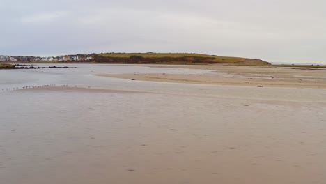 tracking left across sandy beach under overcast skies, a calm and desolate shoreline view, rusheen bay galway ireland