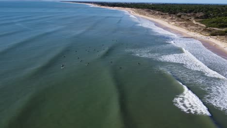 drone-flies-over-the-line-up-of-the-les-grenettes-reef-break-on-the-island-of-ré-in-the-atlantic-ocean,-drone-shot-in-sunny-weather