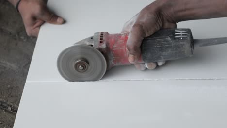 las manos del trabajador de la construcción cortando granito con una molienda de corte