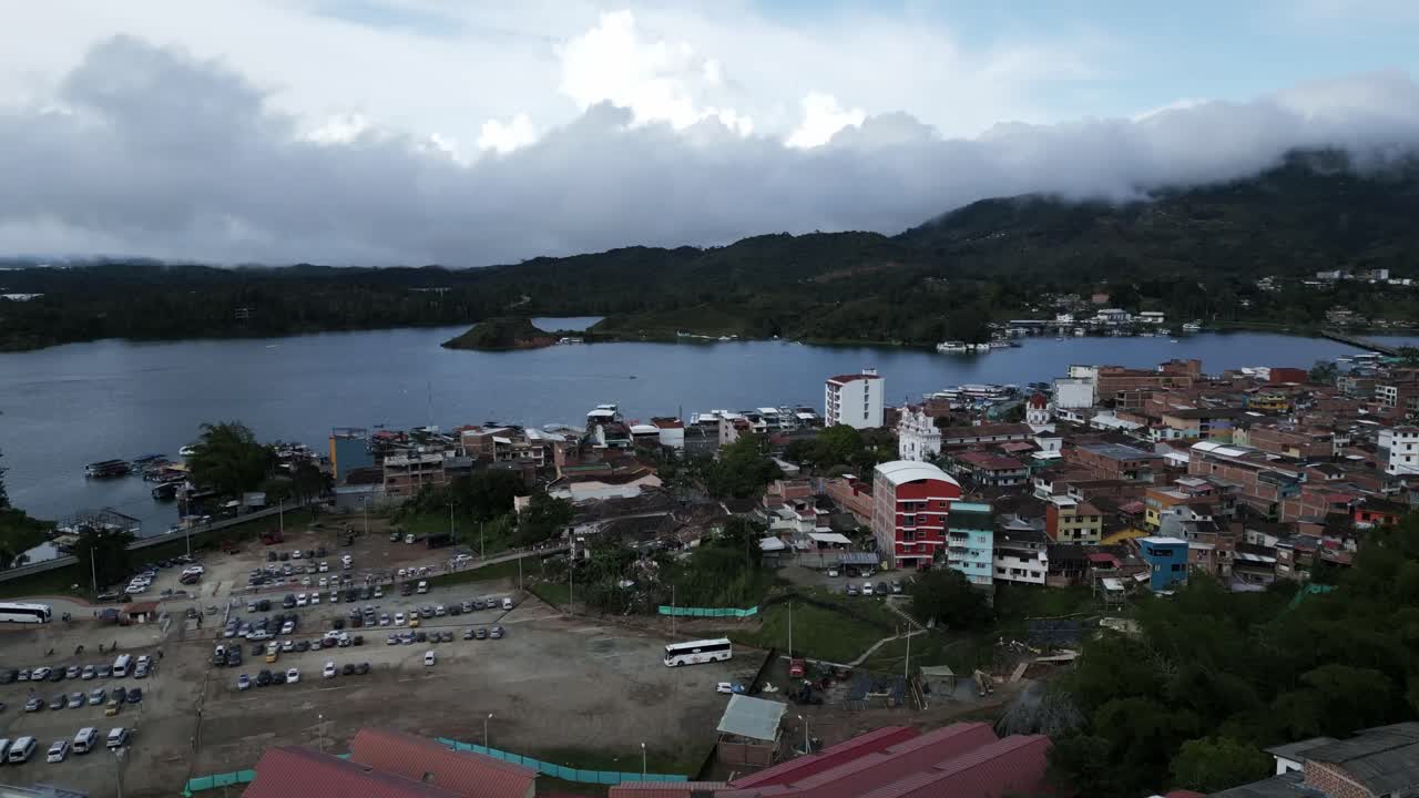 drone aéreo de primera categoría vuela sobre la ciudad de guatape antioquia colinas colombianas, lago que retrata el agua plateada y casas decoradas