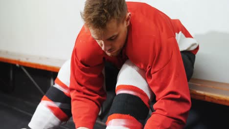 male ice hockey player tying skate in dressing room 4k