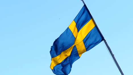 swedish flag fluttering in the wind, blue sky background