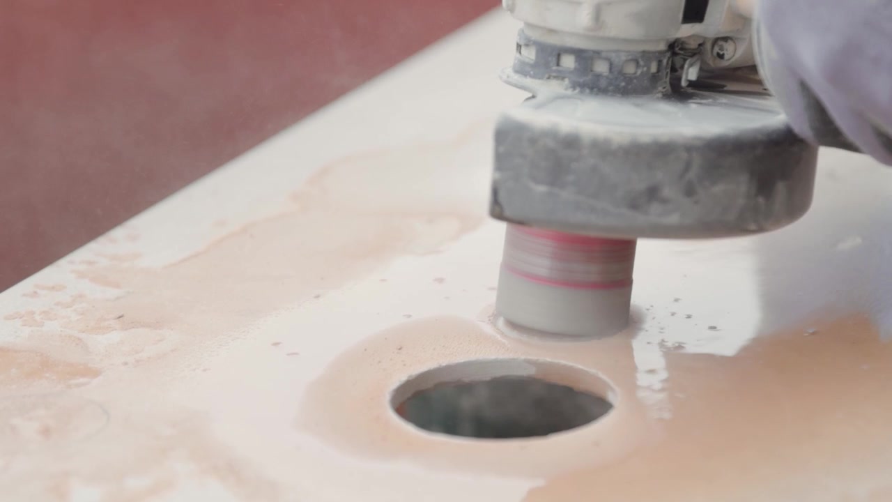 Opening multiple holes in a tile with a power tool. Tile construction worker cutting ceramic tiles.