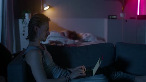 man working on laptop at night on couch