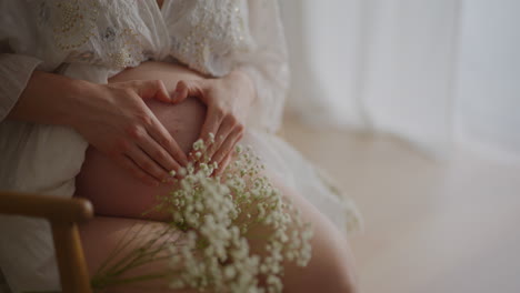 pregnant woman with heart-shaped hands on belly