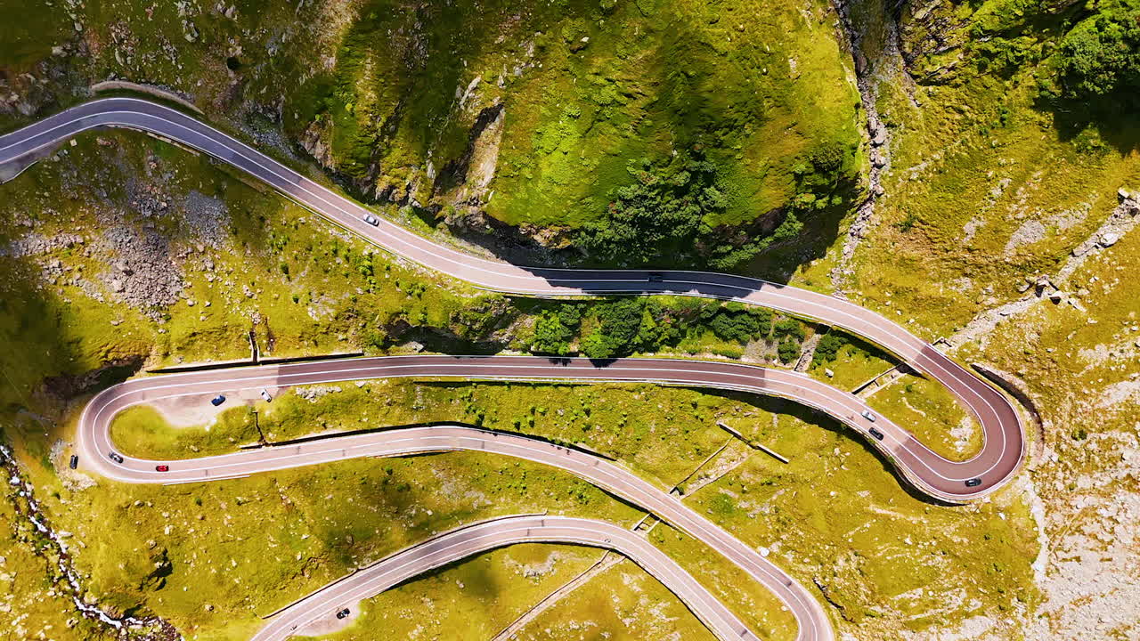 Afdalen boven de spannende weg op de groene helling van de berg. Auto's rijden over de Transfăgărășan in het Karpatengebergte, Roemenië