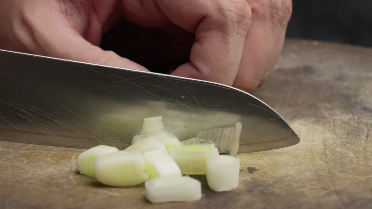 Slicing a fresh leek on a wooden board with a sharp knife