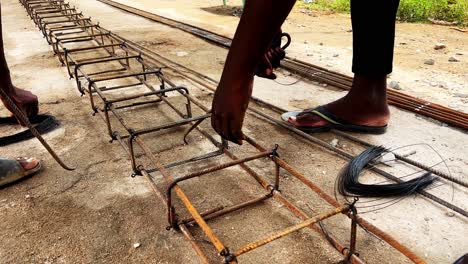 mano de un trabajador de la construcción con la fabricación de una barra de refuerzo de acero, los trabajadores están usando alambre de acero para unir barras de acero