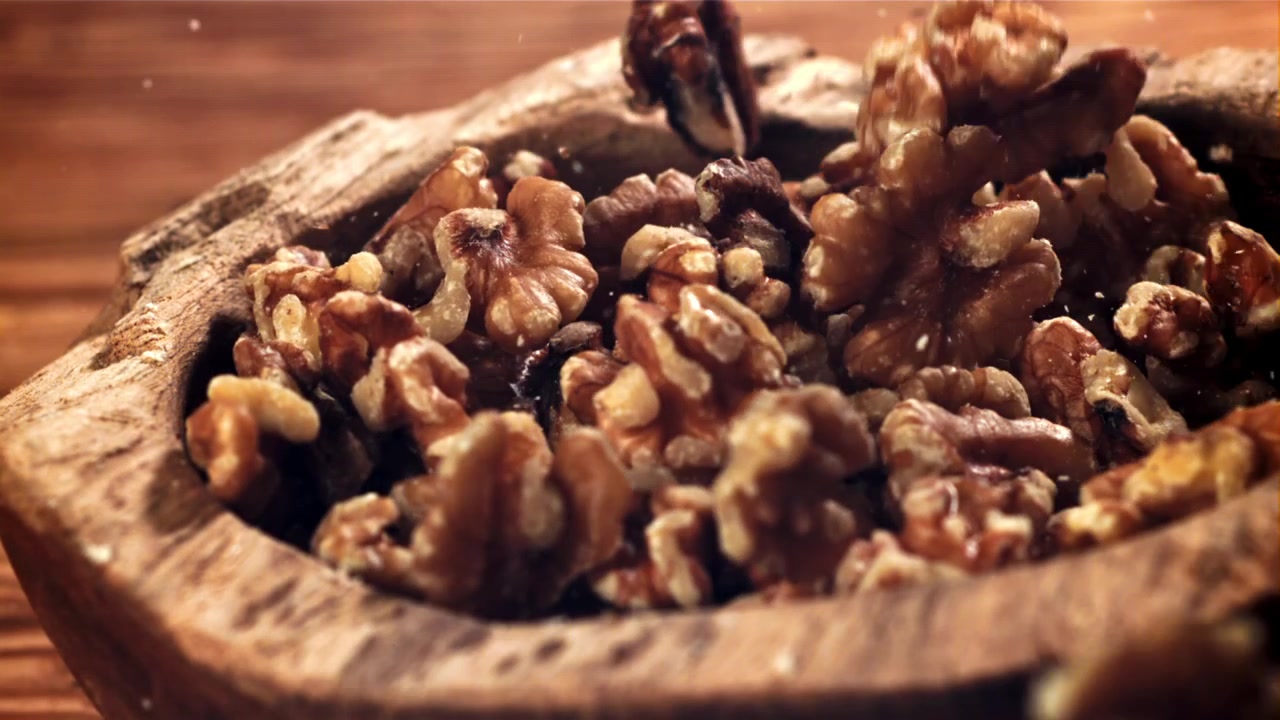 Walnuts Falling into a Rustic Wooden Bowl in Slow Motion