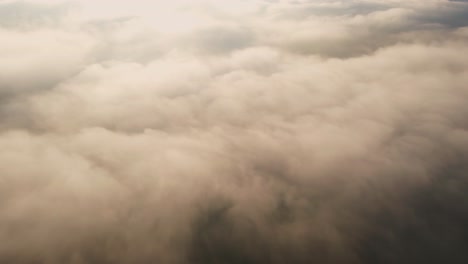 Aerial-view-through-low-hanging-fog-clouds,-sunny-morning-in-Bali,-Indonesia