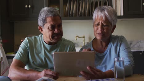 Senior-mixed-race-couple-having-online-medical-consultation-using-tablet