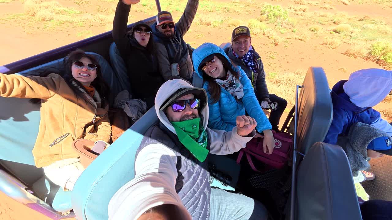 Gruppo di amici felici che viaggia in un veicolo scoperto attraverso un paesaggio desertico