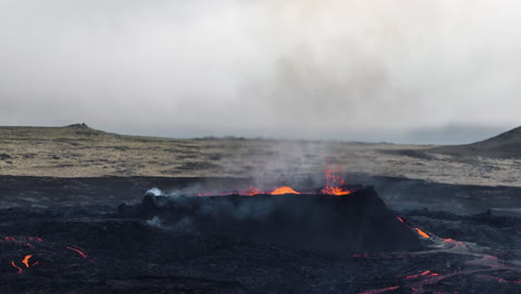 Volcano-in-eruption,-red-hot-magma-boiling-in-crater,-aerial-side-view