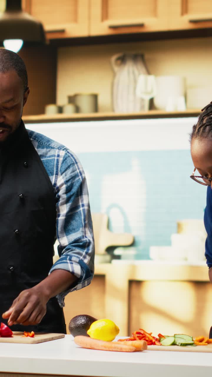 Vertical Video Black couple adding chopped vegetables in a bowl for fresh salad