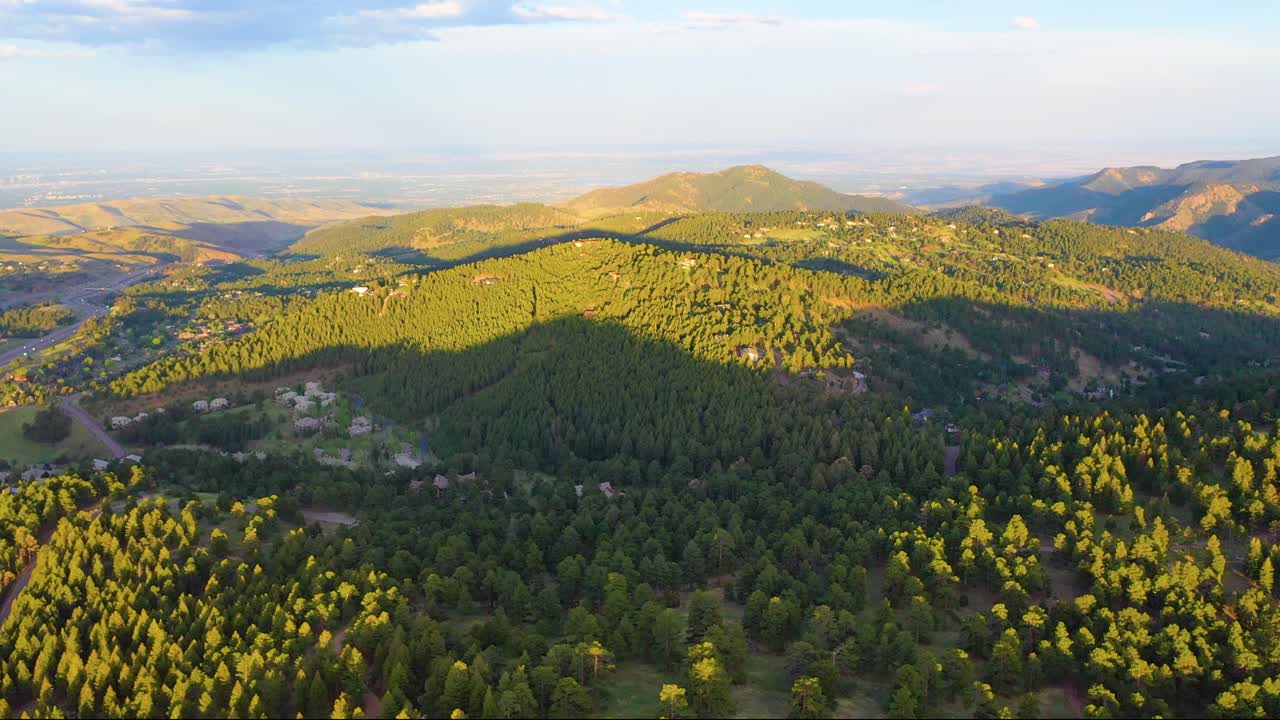 Sweeping cinematic aerial of Colorado Rockies at golden hour, golden light over rugged ridges, shimmering alpine lakes, and lush green meadows, high-quality 4K drone footage perfect for nature lovers