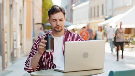 hombre adulto trabajando en línea trabajo remoto con portátil en la ciudad café restaurante navegación sitio web charla