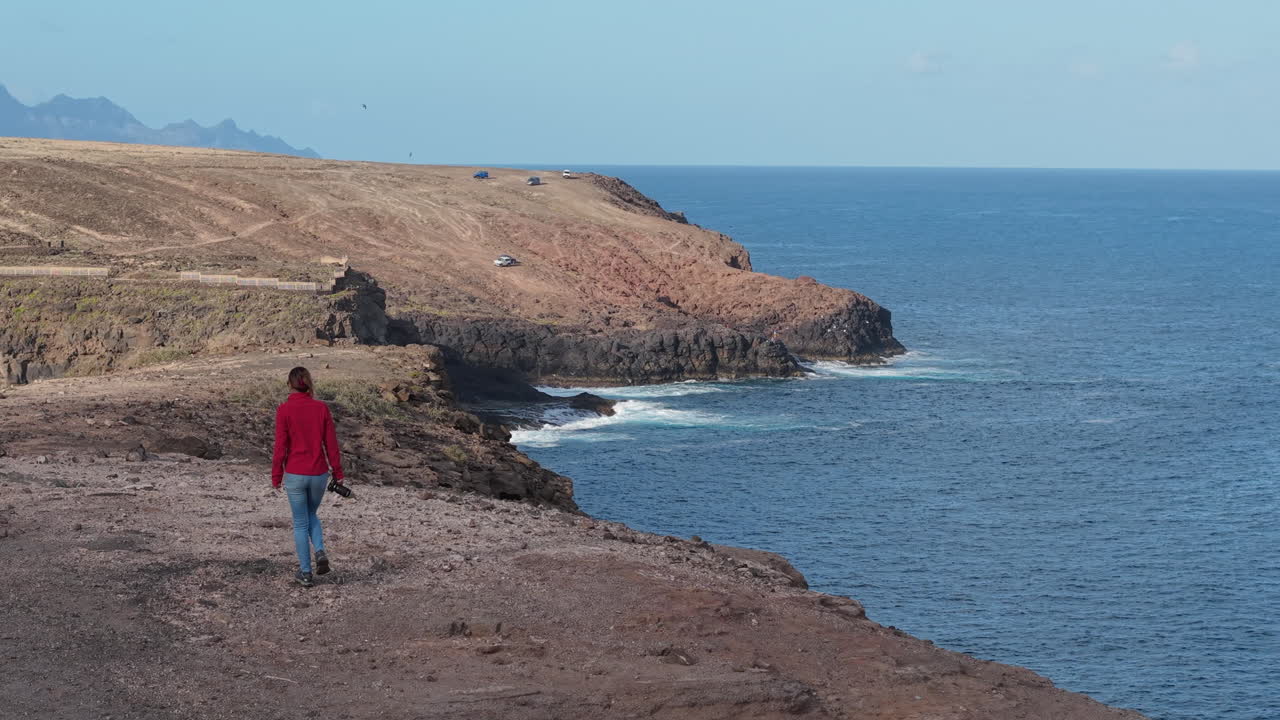 Aerial view of a woman with her camera exploring a cliff on the coast of Gran Canaria, Canary Islands, Spain