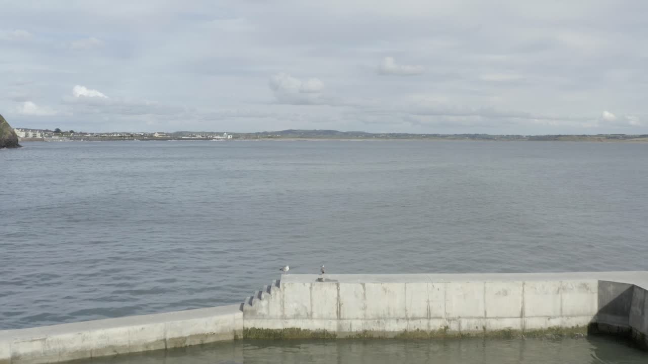 sobrevuelo aéreo bajo del rompeolas de hormigón estrecho en la costa atlántica