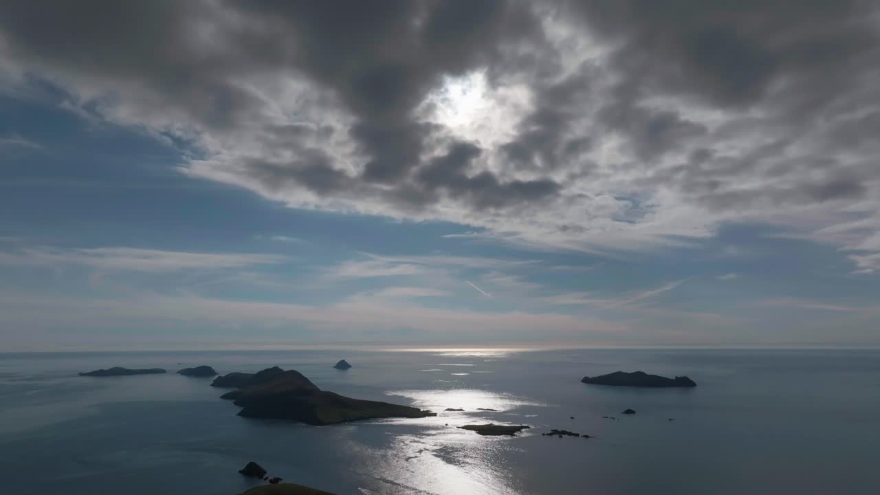 Drammatica ripresa aerea dell'isola di Great Blasket in Irlanda, con raggi di sole che si fanno strada tra nuvole fitte sull'Oceano Atlantico