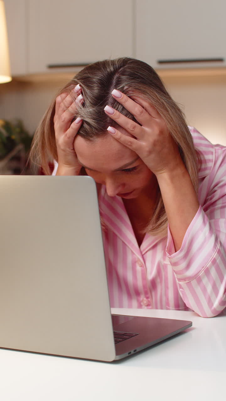 Adult woman freelancer reads tender loss message on laptop frowns shakes head sighs disappointment