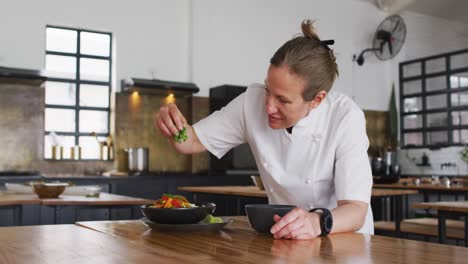 caucasian female chef preparing a dish and smiling in a kitchen