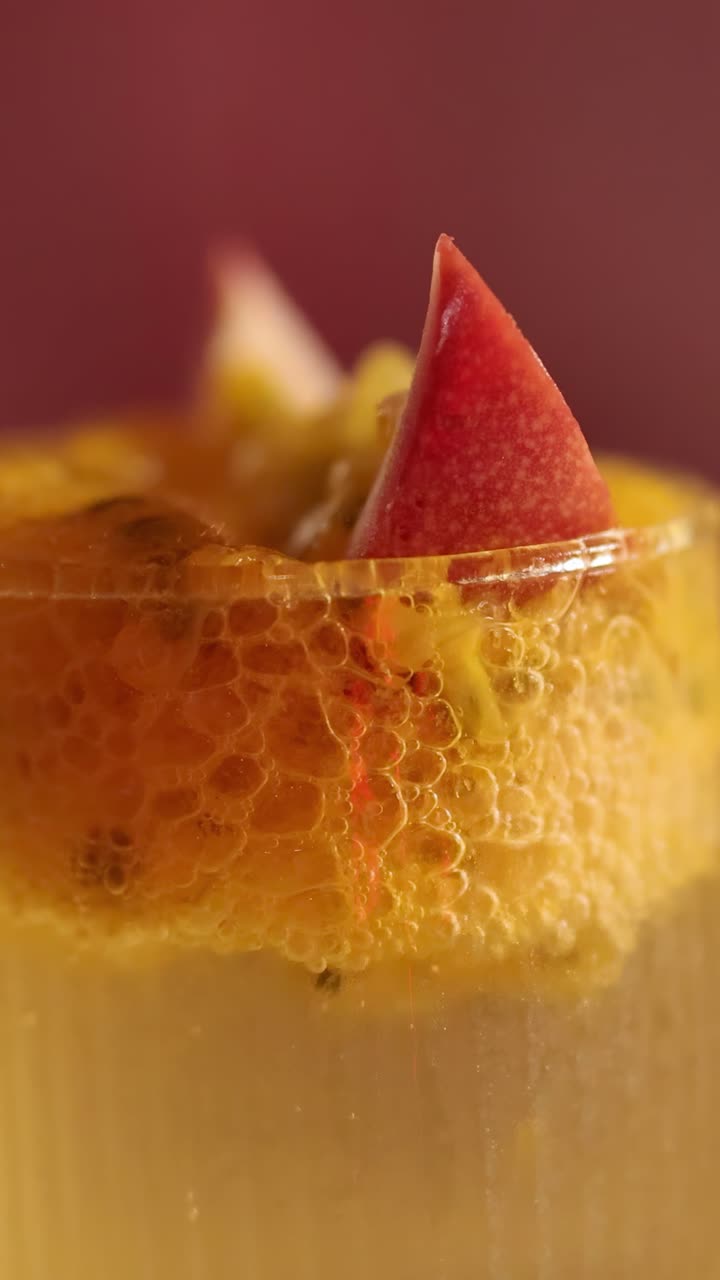 Primo piano di un vivace cocktail al frutto della passione con guarnizione fresca, ripreso con luce calda in un ristorante di Bangkok.