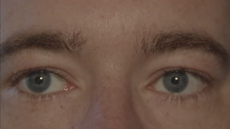 primer plano de un par de ojos azules masculinos mirando alrededor y parpadeando lentamente