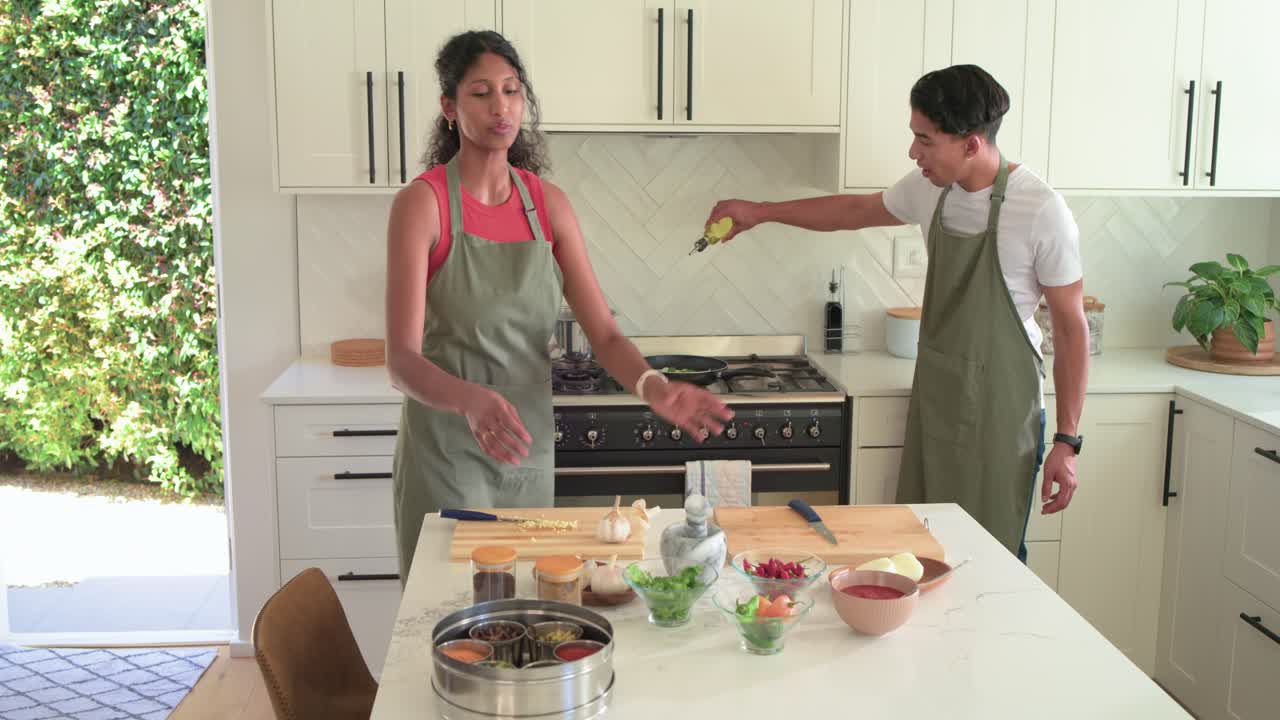 Coanfitriões afro-americanos gesticulando para a panela, preparando tigelas, derramando azeite para cozinhar com ring light.