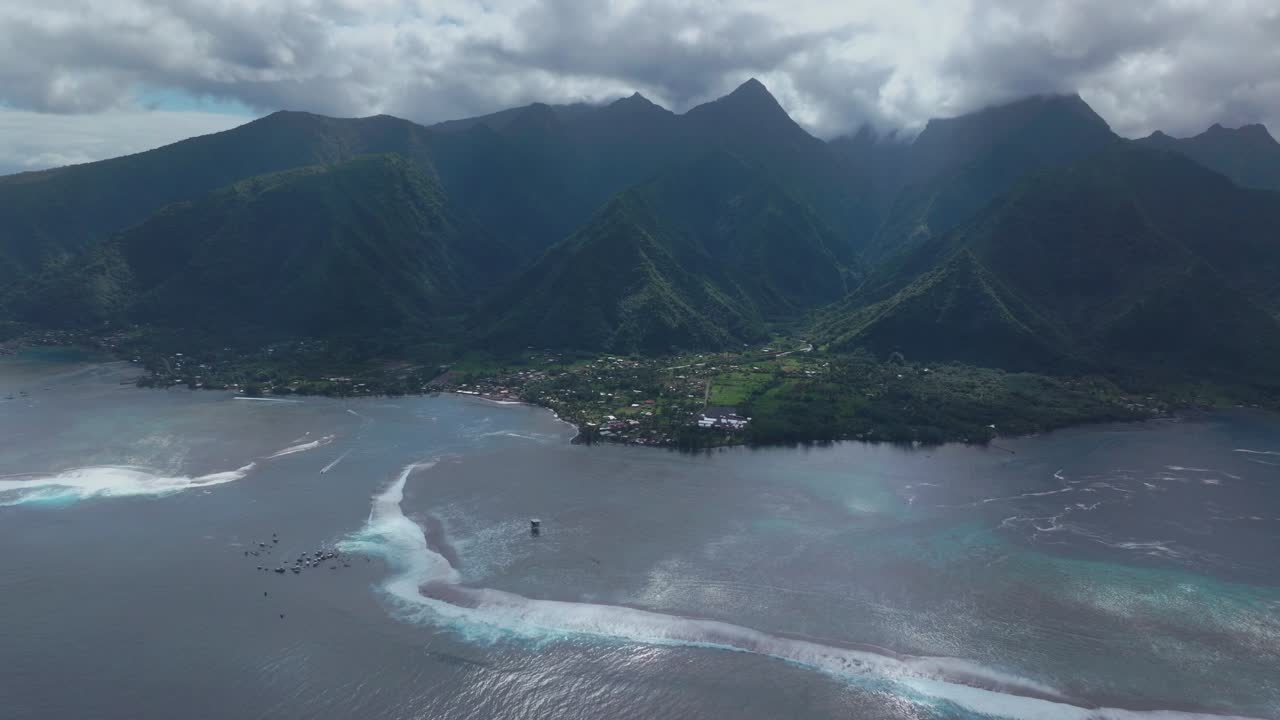 teahupoo costera tahiti vista aérea de drones perspectiva polinesia francesa arrecife de coral olas de surf montañas océano pacífico canal barcos nublado sol de día punto faremahora paso havae círculo a la izquierda