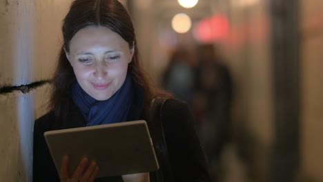 Cheerful-woman-using-pad-in-the-evening-city