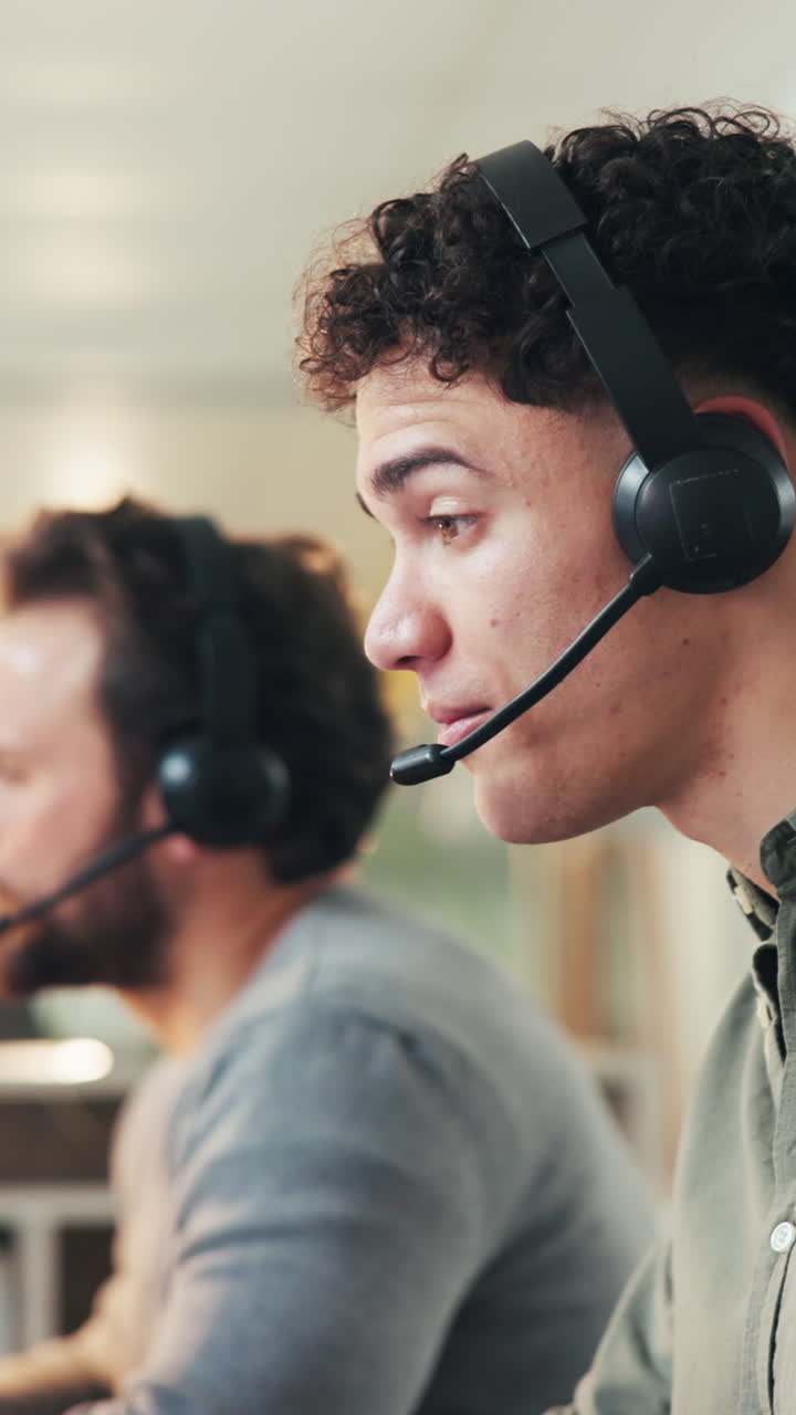 Young Man Talking on Headset in a Call Center