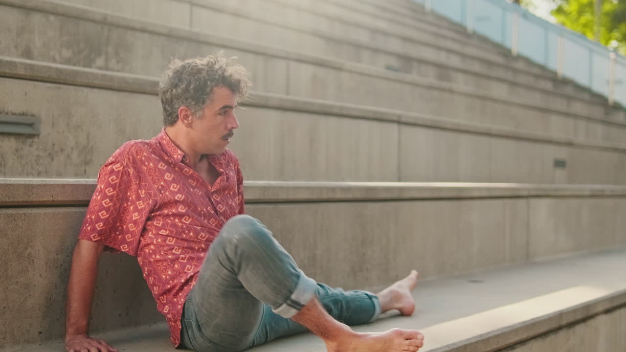 Man Stretching Barefoot on Concrete Steps in Urban Setting