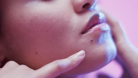 lips of biracial woman with dark hair in blue and pink light, slow motion