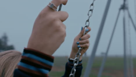 close up hands lonely woman on swing in playground park swinging alone teenage depression concept