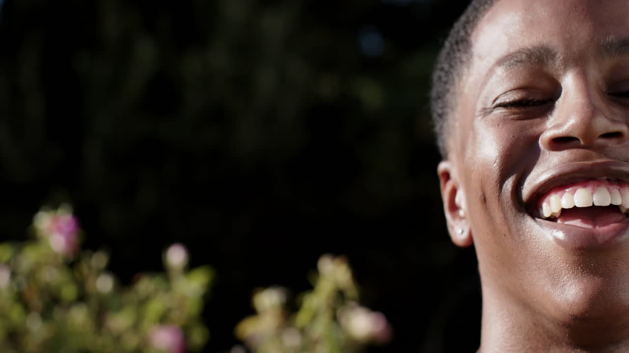 African American man smiling laughing reacting to offscreen voice in garden, ear stud, copy space