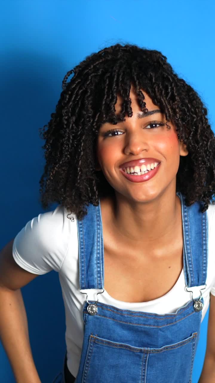 Portrait of a woman with curly hair wearing overalls