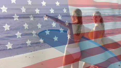 Animation-of-flag-of-usa-over-happy-caucasian-women-with-surfboards-on-beach-in-summer