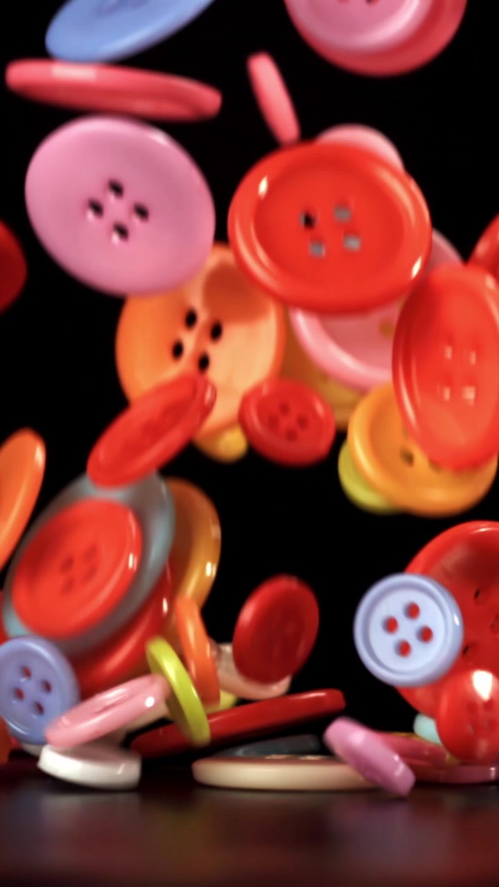 Colorful Buttons Falling in Slow Motion on Black Background