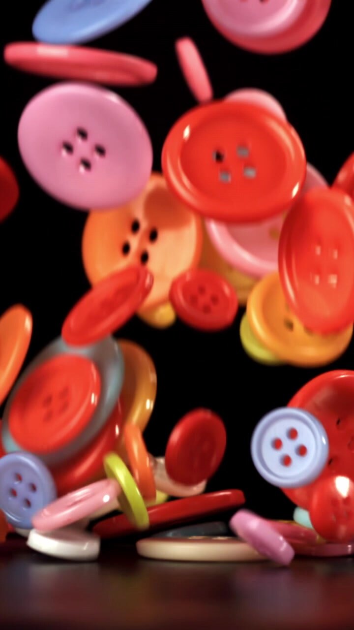 Colorful Buttons Falling in Slow Motion on Black Background