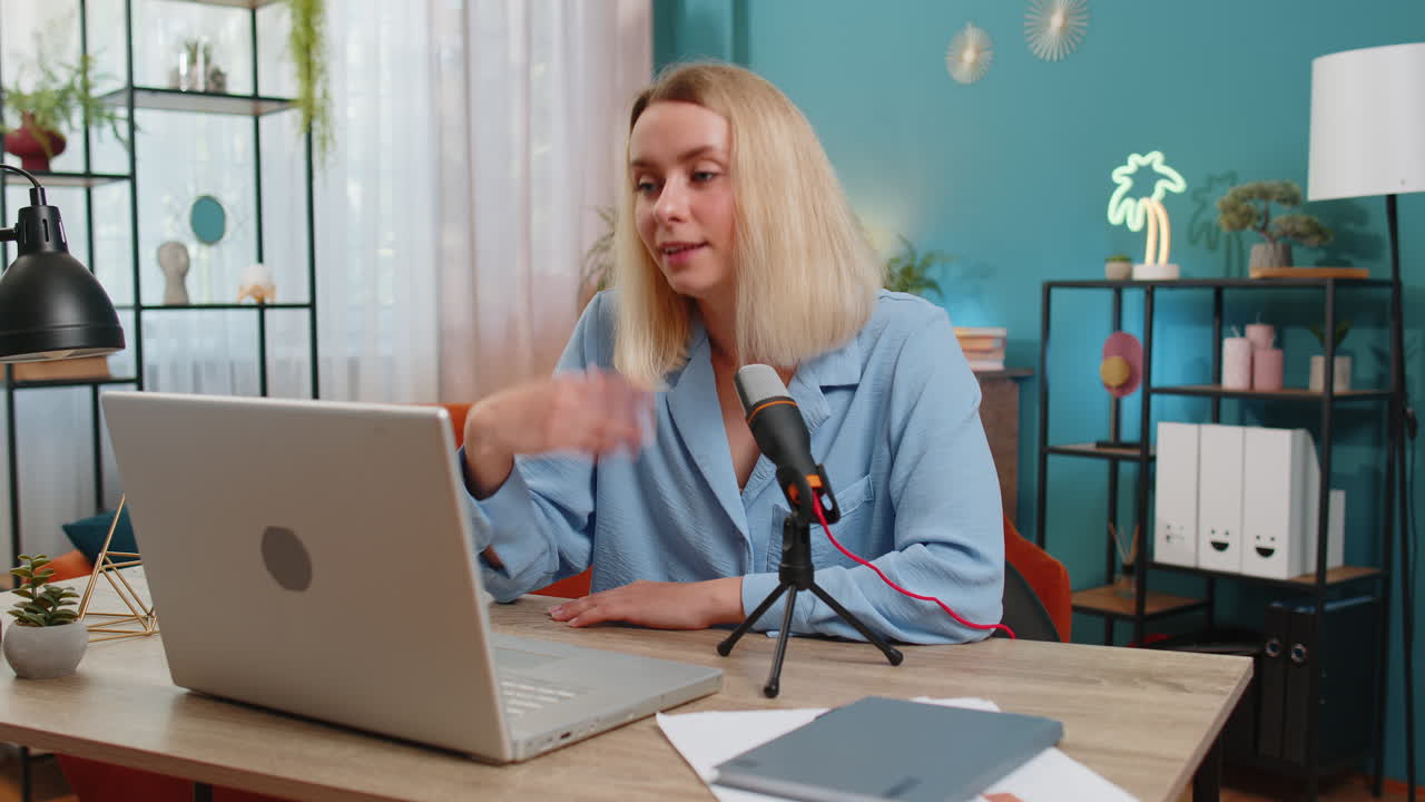 Happy blogger woman recording podcast at desk, giving workshop webinar speaking at microphone laptop