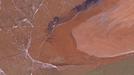 Sanfte-Flache-Wellen,-Die-An-Einem-Hellen-Tag-Gegen-Eine-Wunderschöne-Orangefarbene-Sandbank-Oder-Untiefe-Streichen