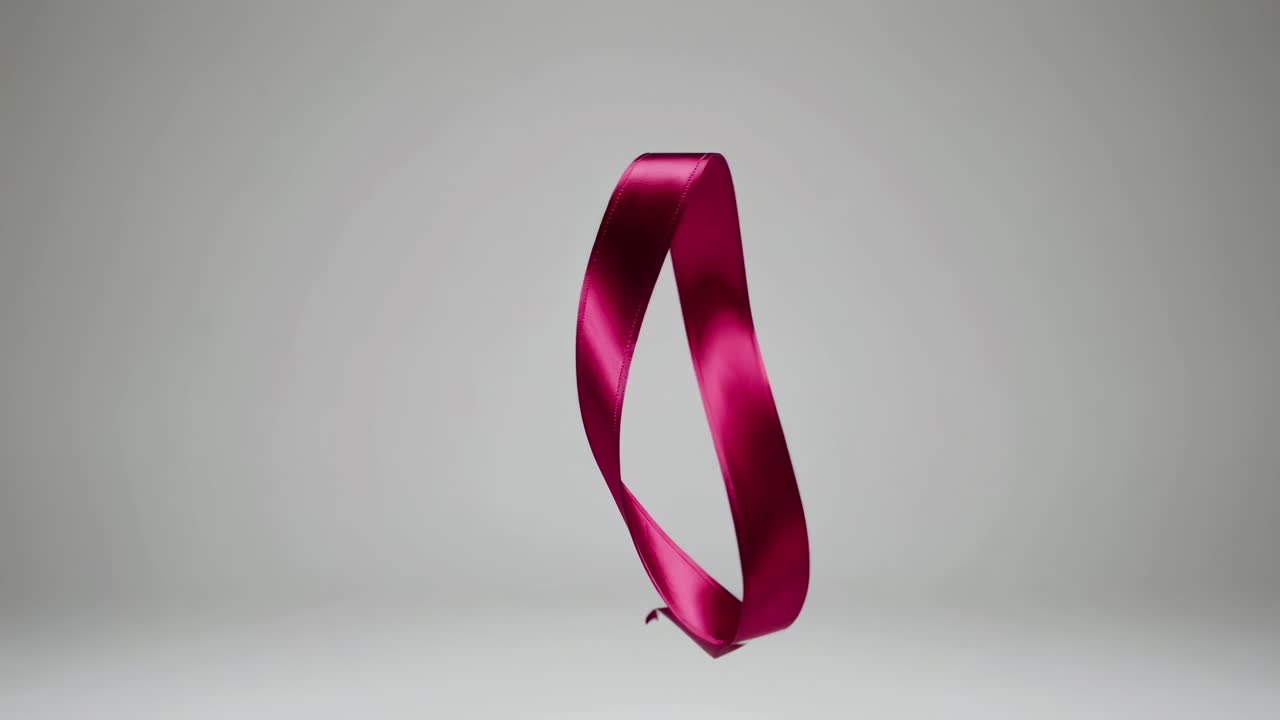 A sleek, red ribbon twists elegantly against a neutral backdrop