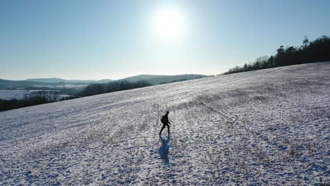 a man walking up a frozen hill - clear skies and sunny