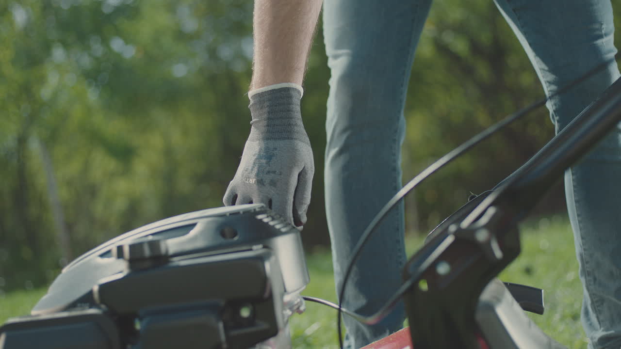 hombre comenzando una cortadora de césped