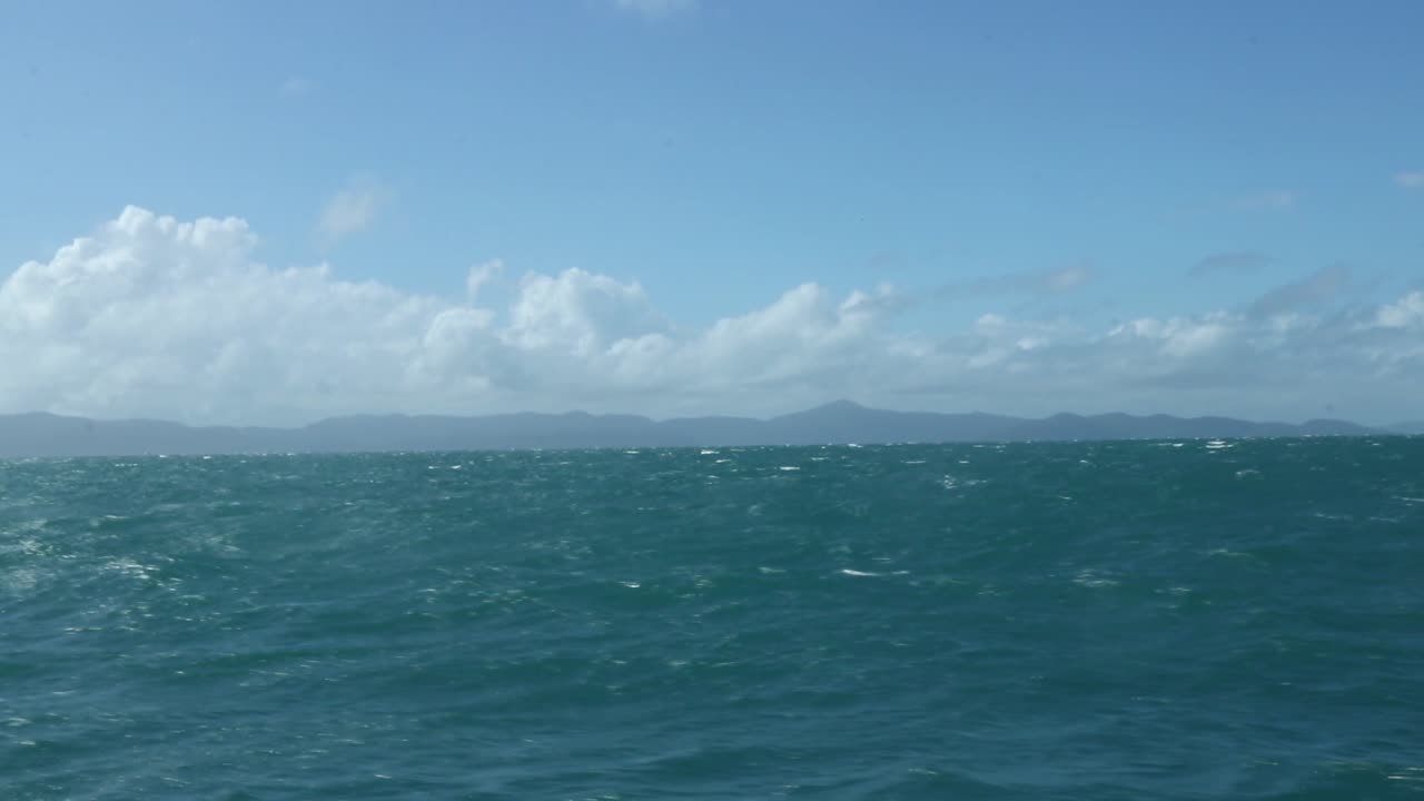 Rolling blue waves in the ocean with land in the distance.