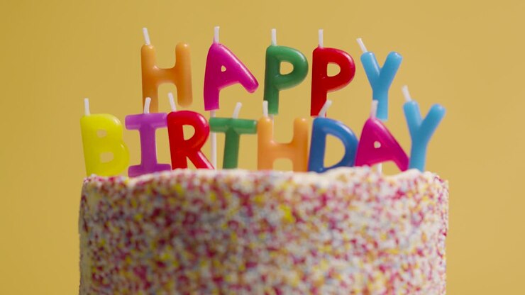 Studio Shot Of Revolving Birthday Cake Covered With Decorations And Candles Spelling Out Happy Birthday 3