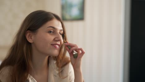 Portrait-of-a-beautiful-girl-doing-a-facial-massage-with-a-jade-roller-in-front-of-a-mirror