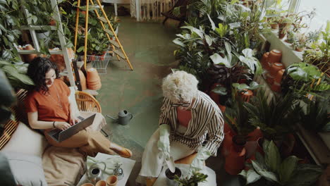 girls working on laptop and planting flower in shop