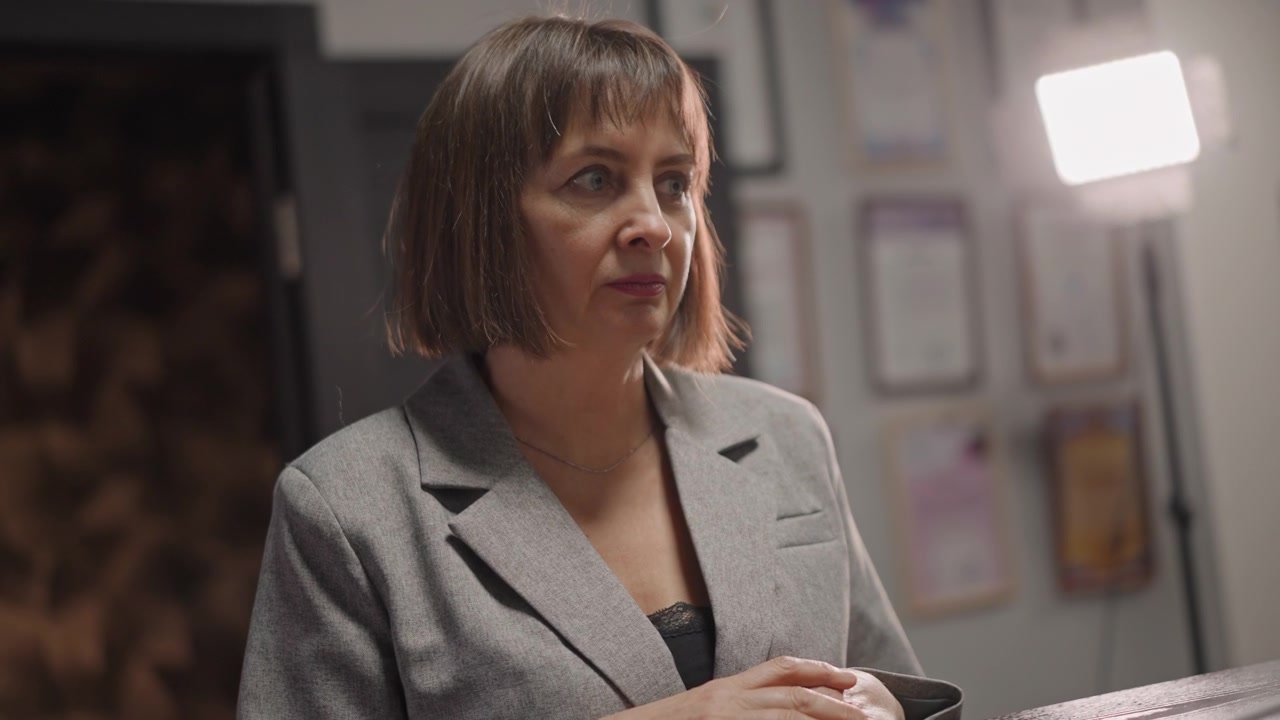 Miembro del personal examinando documentos y certificados expuestos visiblemente. Recepcionista revisando diligentemente documentos de presentación con certificados personales prominentemente exhibidos en el fondo